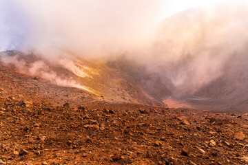 Side view of the crater opening of erupting volcano. Crater with vulcanic gas fumaroles. Clouds and...