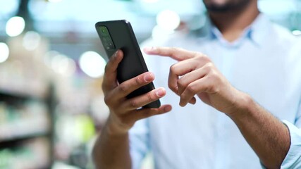 Сlose up male hand using smartphone communication with light bokeh standing indoor shopping center mall or supermarket Man use online app for discount, sale promotions use mobile phone Closeup