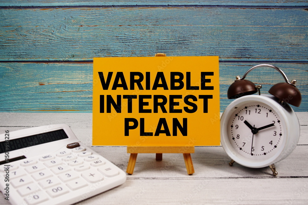 Poster variable interest plan text written on paper card with calculator and alarm clock on wooden backgrou