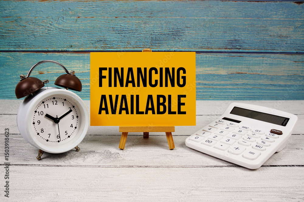 Poster financing available text written on paper card with calculator and alarm clock on wooden background