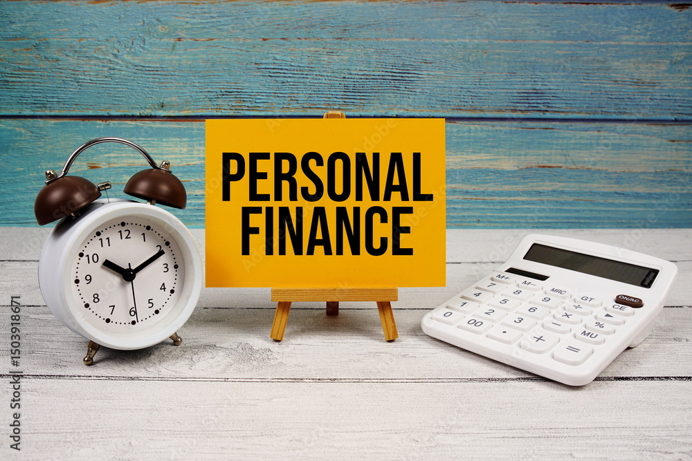 Poster personal finance text written on paper card with calculator and alarm clock on wooden background