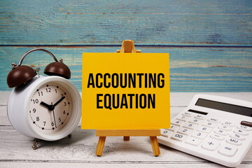 Accounting Equation text written on paper card with calculator and alarm clock on wooden background