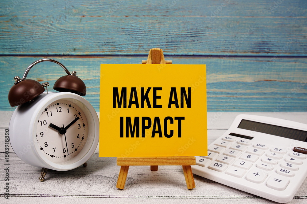 Poster make an impact text written on paper card with calculator and alarm clock on wooden background