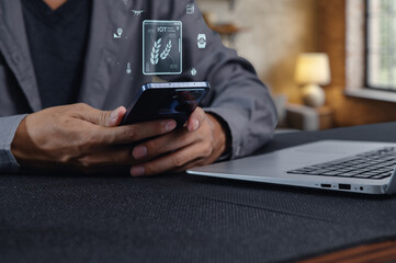 Hands Using Smartphone with IoT Graphics and Laptop on Table