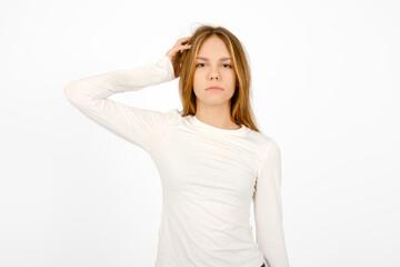 Young woman in a white long-sleeve shirt poses confidently with a thoughtful expression