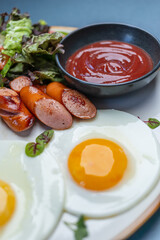 Traditional English breakfast with fried eggs, bacon, sausages, baked beans, grilled tomatoes, mushrooms, and toast. Hearty morning meal. Top view, close-up.

