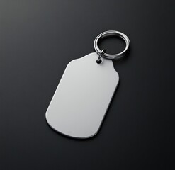 Fototapeta premium A blank, silver, dog tag-shaped keychain with a metallic ring, rests on a dark surface