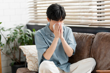 ティッシュで鼻をかんでいる若い日本人男性。
