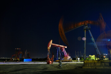 Oil rig at the background of refinery by night. Oil and gas industry.