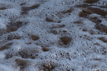 Coastal Eruption: Wave Foam Detail on Sandy Beach