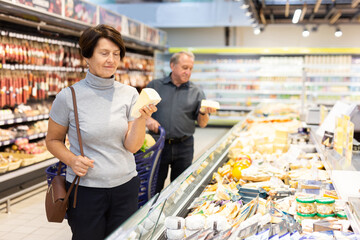 Elderly female customer looking around in dairy section of supermarket