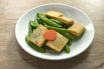 stir fried garden pea and carrot with slice tofu in soy sauce vegetarian food on dish