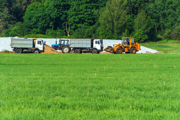 Loading grain into trucks for transportation. Agricultural machinery in the field. Harvest time. Transportation of wheat.