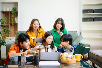 Diverse group of happy young adults collaborating on a laptop in a cozy, modern room. Ideal for teamwork, e-learning, startup, study group, and creative lifestyle