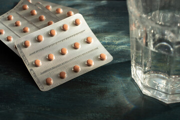 pink pharmaceutical remedies on blue background with a glass of water