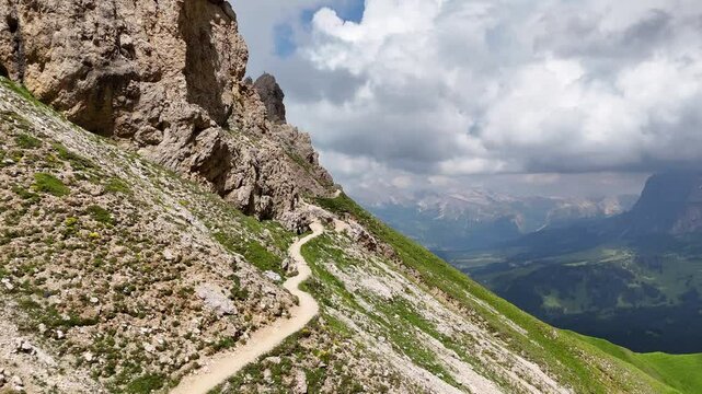 Forward drone flight above mountains and hiking trail near tierser Alpl, Rifugio Alpe di Tires towards Forcella Denti di Terrarossa. Mountain slope with trail, and view in the valley. Wonderful Dolomi