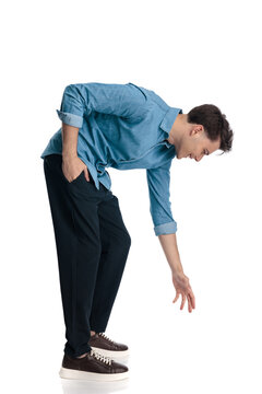 side view of happy casual guy bending over and picking up something from floor