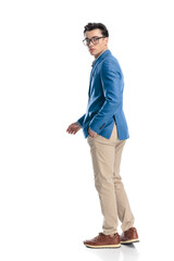 Fototapeta premium side view of attractive young man with glasses moving with hand in pocket