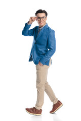 happy young man with glasses walking with hand in pocket and fixing glasses