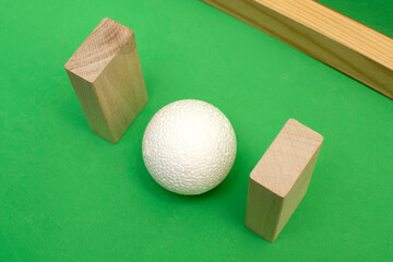 Still life with wooden blocks and a a plastic foam ball on green background	