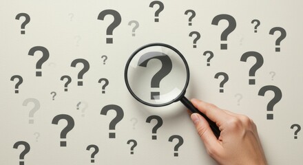 Hand Holding Magnifying Glass to Search for Answers Among Scattered Question Marks