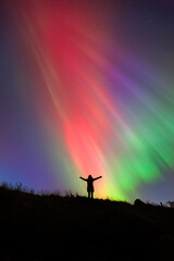 Fototapeta premium Woman Silhouette with Northern Lights, Ireland – Colorful Aurora Borealis Sky
