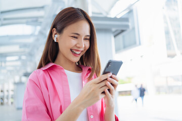 Fototapeta premium Beautiful young Asian woman using smartphone in public areas, During leisure time. The concept of using the phone is essential in everyday life.