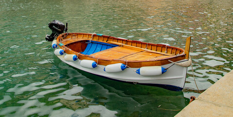 Obraz premium Classic wooden boat floating in Vernazza's harbor with colorful houses behind...