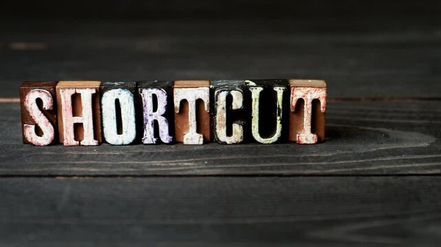SHORTCUT Concept. Alphabet blocks on a wooden texture background. 4K