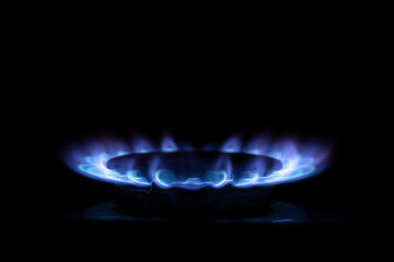 Gas burner flame on kitchen stove in dark in apartment