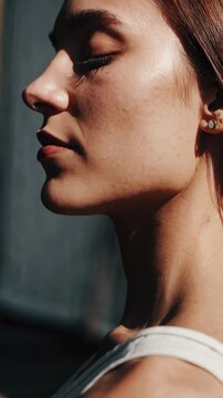 Close-up profile of a woman in soft lighting, highlighting serene expression. Shot from a side angle, ideal for a calming, introspective video.