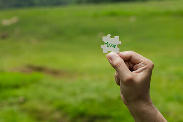 Hand Holding Puzzle Piece with ESG Concept in Natural Setting