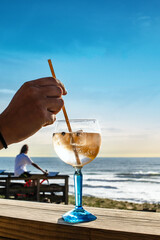 Young woman drinking a gin and tonic on a terrace. facing the ocean