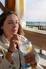 Beautiful young woman drinking a gin and tonic on a terrace.