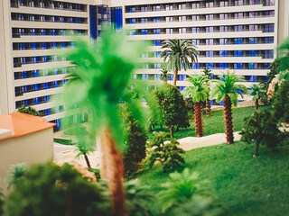 A model of a multi-story modern house surrounded by artificial trees and a lawn. Close-up, selective focus.