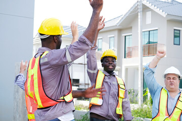 A team of male engineers wearing safety helmets is standing and planning at the construction site.