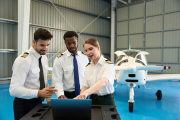 Aircraft maintenance crew using laptop in hangar with small airplane © alvaro