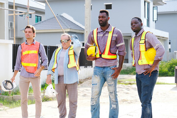 Obraz premium A team of male engineers wearing safety helmets is smiling while standing at the construction site.
