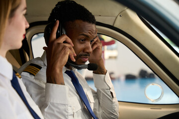Student pilot adjusting headset in cockpit with instructor beside him