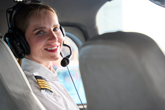 Smiling female pilot wearing headset in airplane cockpit