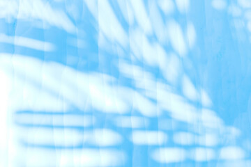Blue palm leaves shadow on white paper texture background, blank white paper with leaves pattern background, blue filter effect