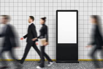 Blank vertical digital advertising display with people walking by in motion blur in tiled subway...