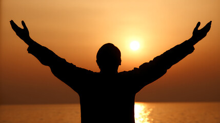 Fototapeta premium A man is standing on a beach with his arms raised in the air
