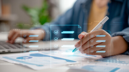 Businesswoman working with a digital checklist and analytics report, using a laptop and pen for productivity management and task organization in a modern business environment.