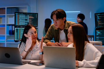 Fototapeta na wymiar Asian software engineer or programmer team working late in development office,problem solving or algorithm of ai assistant helping for work.software developer,digital technology security concept
