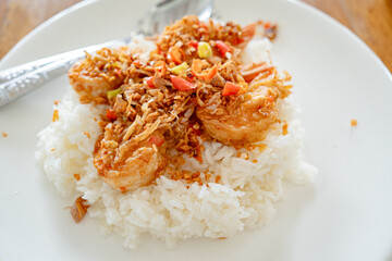 Stir Fried Shrimp and cooked rice topped  in white plate on wooden table at restaurant.Top view