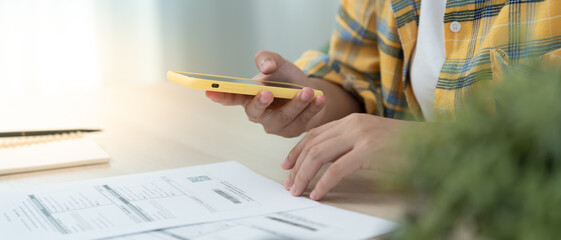 woman use phone to scan barcode or QR codes to pay credit card bill after receiving document...