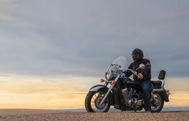 Real photo of a man on motorcycle in desert during sunset with dramatic clouds — concept of freedom, travel, solitude, adventure, and outdoor lifestyle in wild open landscapes