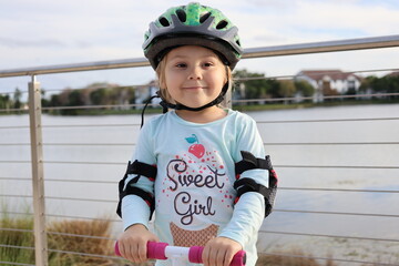 little girl wear cycle helmet riding on scooter