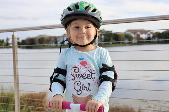 little girl wear cycle helmet riding on scooter